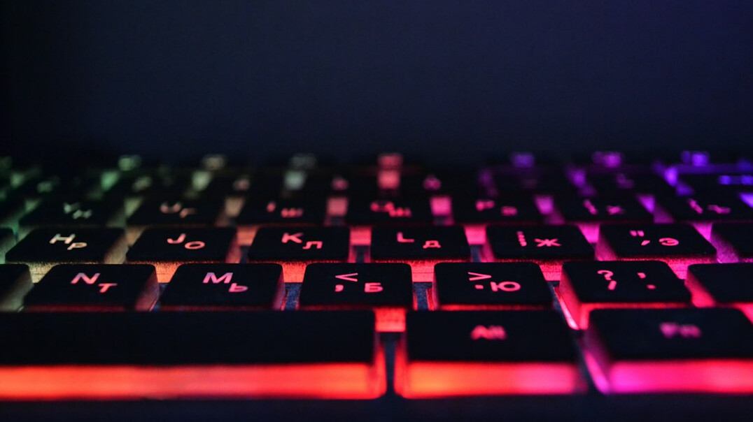 Hands typing code on a laptop screen with colorful syntax highlighting