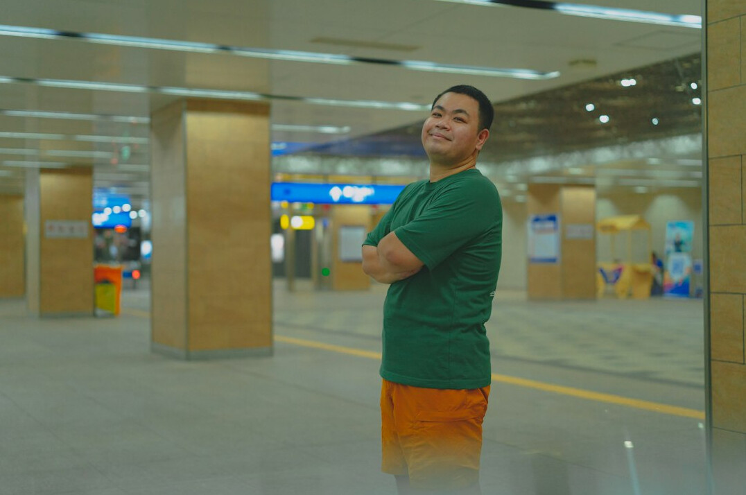 Confident Japanese male programming instructor smiling with arms crossed